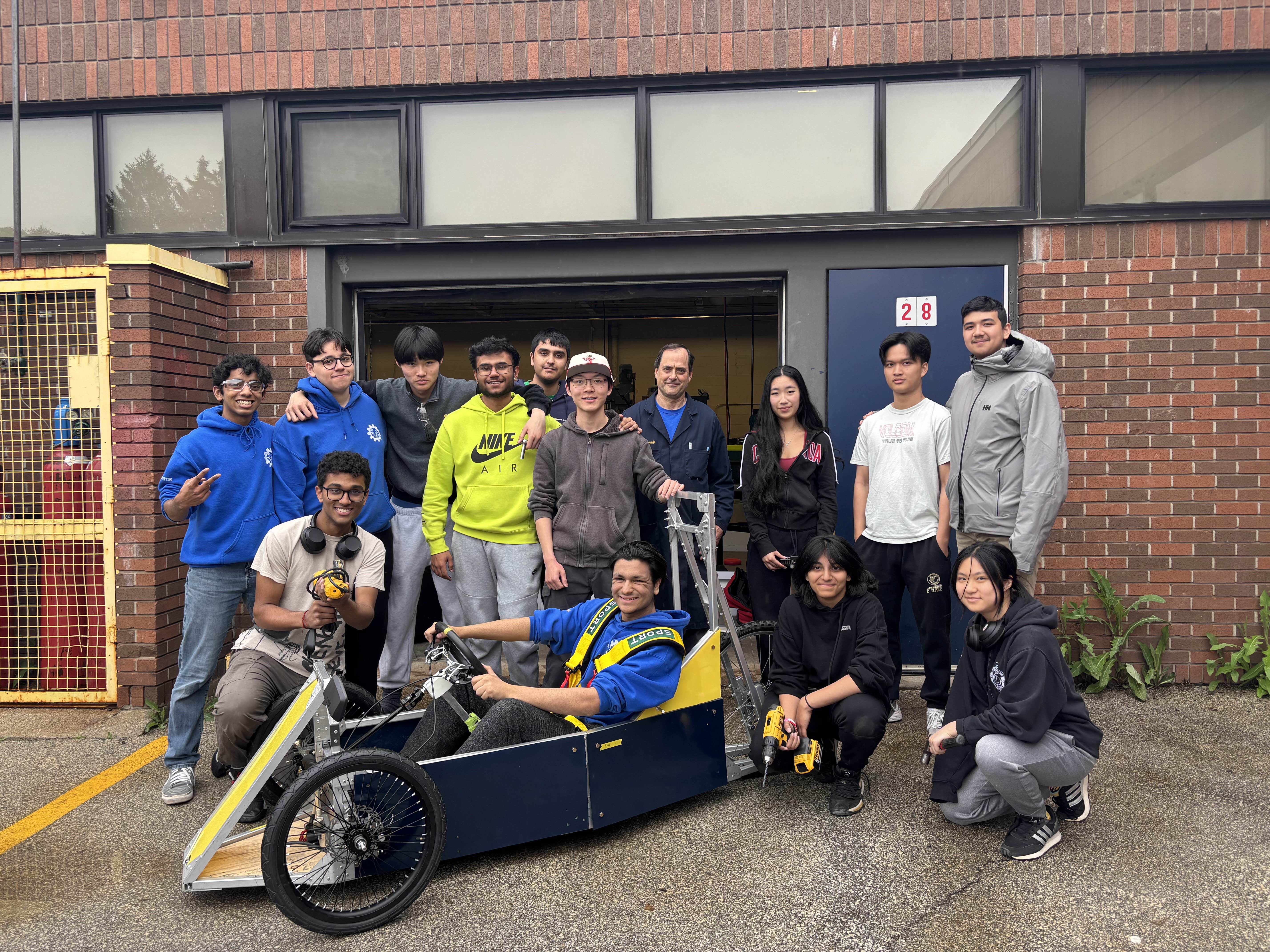 The WOSS Electrathon team gathered around their car outside the school