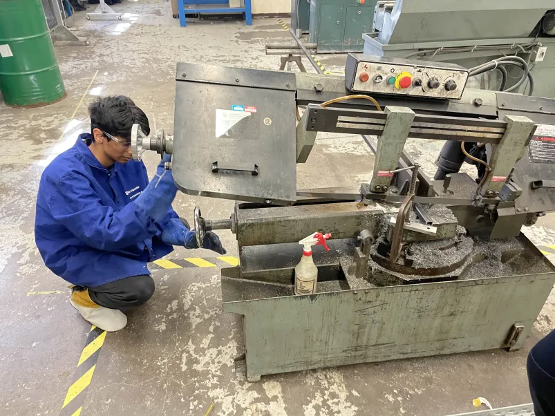 A team member cutting frame stock on the shop bandsaw